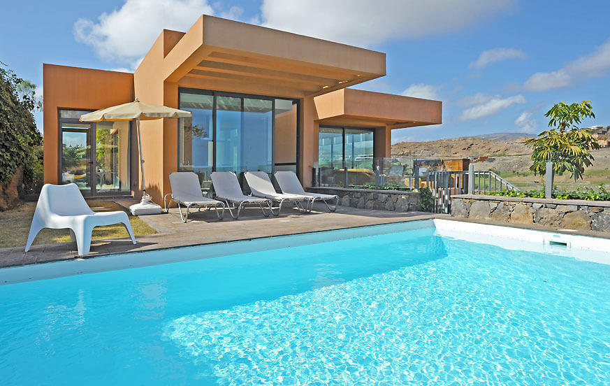 Modernt hus med stora glasfönster, privat pool och panoramautsikt över golfbanan från terrassen
